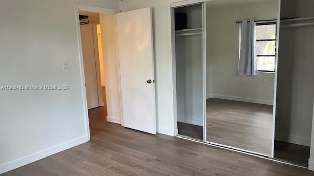unfurnished bedroom with a closet, wood finished floors, and baseboards