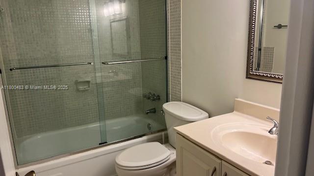 bathroom featuring toilet, vanity, and combined bath / shower with glass door