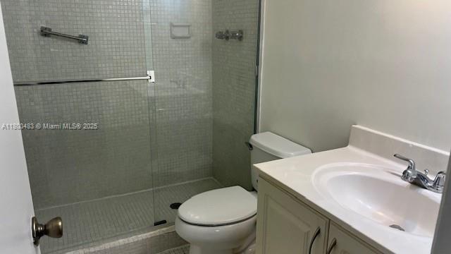 bathroom with a shower stall, toilet, and vanity