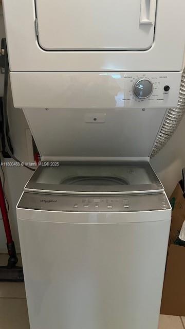 clothes washing area with stacked washing machine and dryer and tile patterned flooring