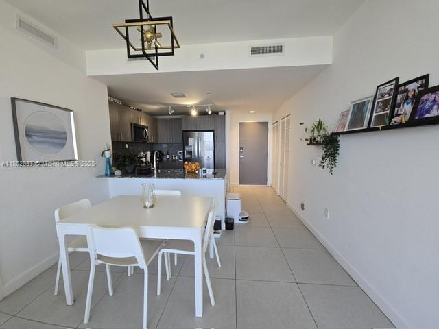 5350 NW 84th Ave Unit 1207, Doral, FL 33166 - dining area featuring track lighting, light tile patterned flooring, a chandelier, and baseboards