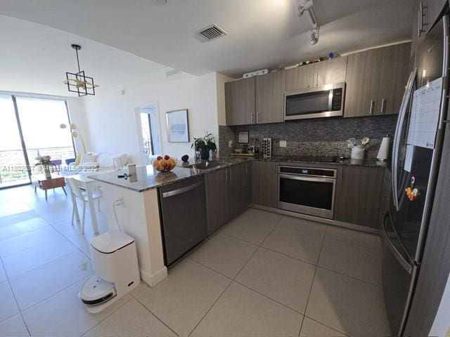 5350 NW 84th Ave Unit 1207, Doral, FL 33166 - kitchen featuring appliances with stainless steel finishes, light tile patterned flooring, a peninsula, tasteful backsplash, and hanging light fixtures