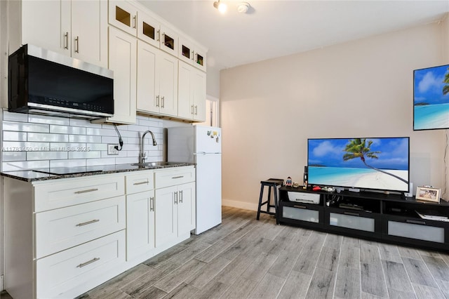 6345 Collins Ave Unit 522, Miami Beach, FL 33141 - kitchen featuring stainless steel microwave, a sink, freestanding refrigerator, dark stone countertops, and light wood-style flooring