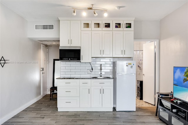 6345 Collins Ave Unit 522, Miami Beach, FL 33141 - kitchen with freestanding refrigerator, stainless steel microwave, a sink, backsplash, and white cabinets