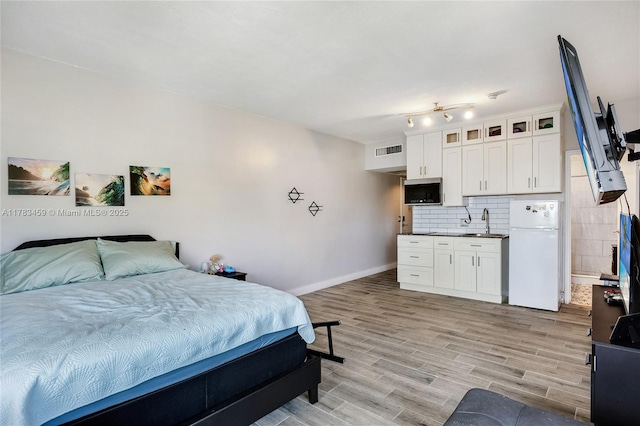 6345 Collins Ave Unit 522, Miami Beach, FL 33141 - bedroom with freestanding refrigerator, a sink, baseboards, and light wood finished floors