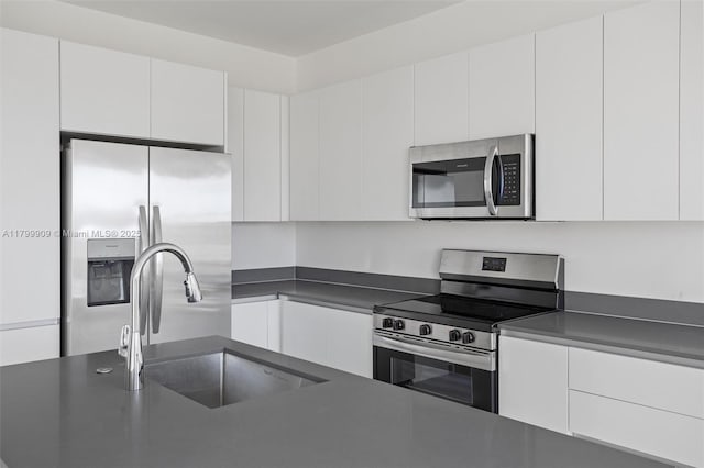 18953 SW 344th Ter, Homestead, FL 33034 - kitchen featuring stainless steel appliances, dark countertops, a sink, and white cabinetry