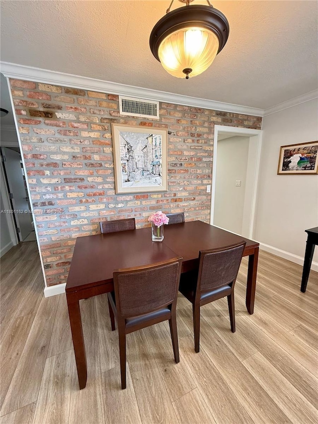 16518 NE 26th Ave Unit 405, North Miami Beach, FL 33160 - dining room featuring baseboards, brick wall, light wood-style flooring, crown molding, and a textured ceiling