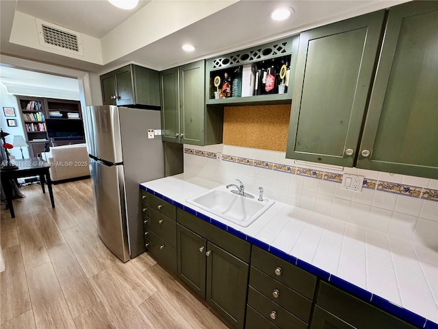 16518 NE 26th Ave Unit 405, North Miami Beach, FL 33160 - kitchen with green cabinets, tile countertops, freestanding refrigerator, a sink, and light wood-style floors