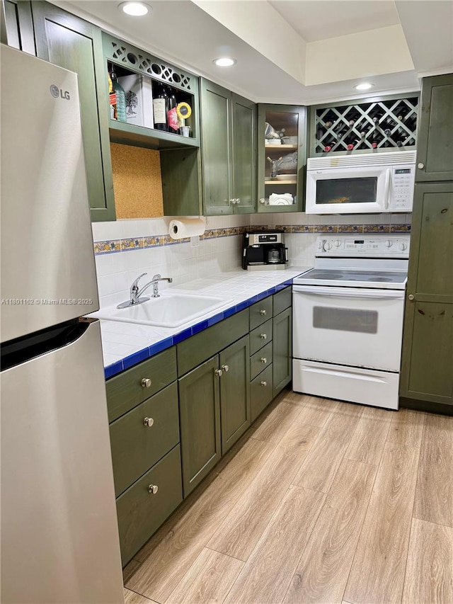16518 NE 26th Ave Unit 405, North Miami Beach, FL 33160 - kitchen with green cabinets, white appliances, a sink, tile countertops, and light wood-type flooring