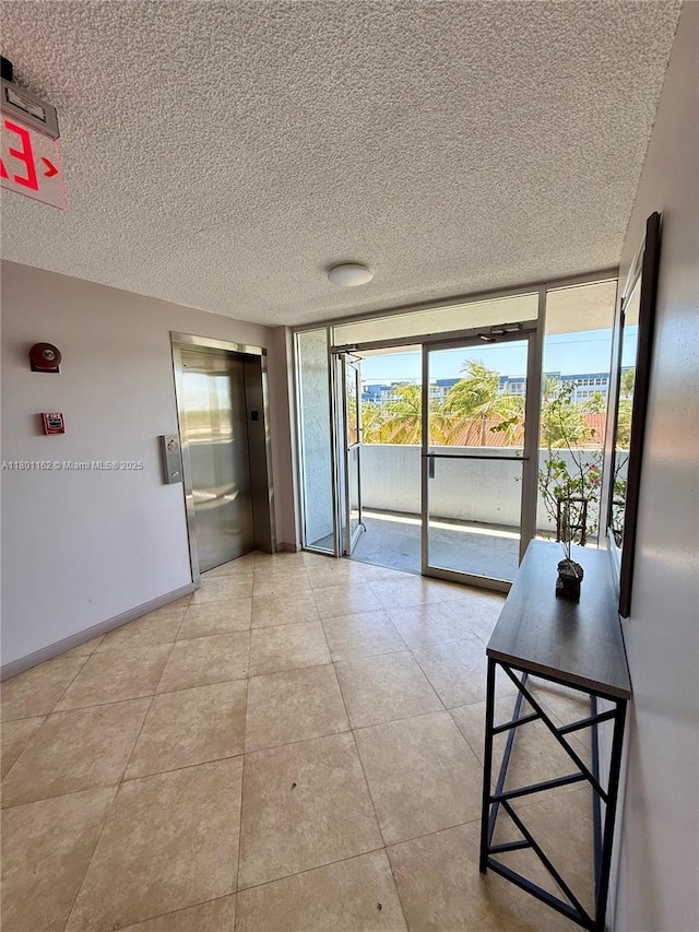 16518 NE 26th Ave Unit 405, North Miami Beach, FL 33160 - empty room with a textured ceiling, elevator, healthy amount of natural light, expansive windows, and light tile patterned floors