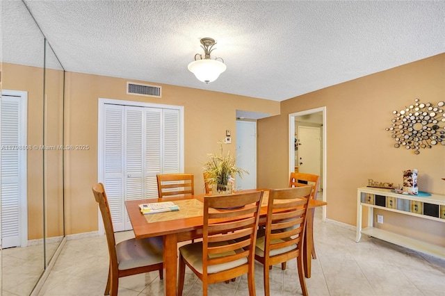 dining space featuring a textured ceiling, baseboards, and light tile patterned flooring