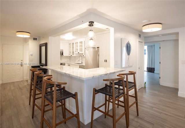 6061 Collins Ave Unit 7D, Miami Beach, FL 33140 - kitchen with fridge, a sink, a breakfast bar area, and white cabinetry