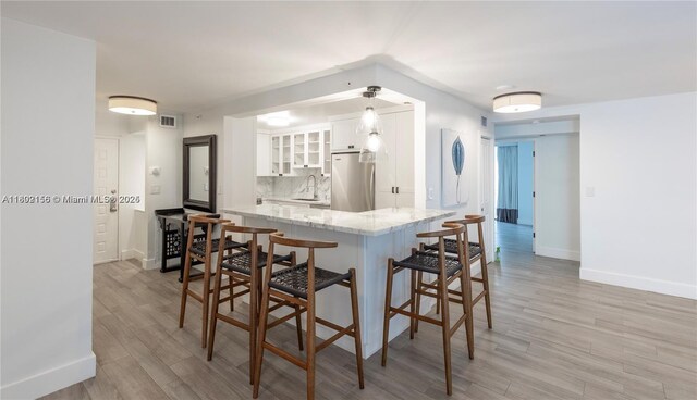 6061 Collins Ave Unit 7D, Miami Beach, FL 33140 - kitchen featuring freestanding refrigerator, white cabinetry, baseboards, and light wood-style floors