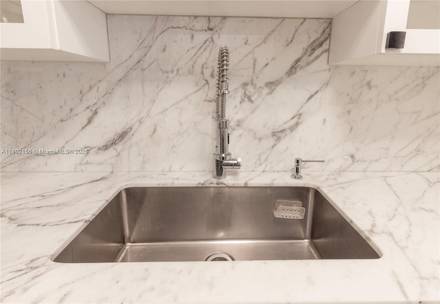 6061 Collins Ave Unit 7D, Miami Beach, FL 33140 - kitchen view of a sink, light stone counters, and white cabinetry