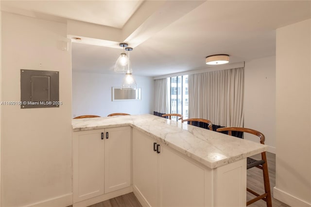 6061 Collins Ave Unit 7D, Miami Beach, FL 33140 - kitchen with a breakfast bar, baseboards, electric panel, and light stone counters