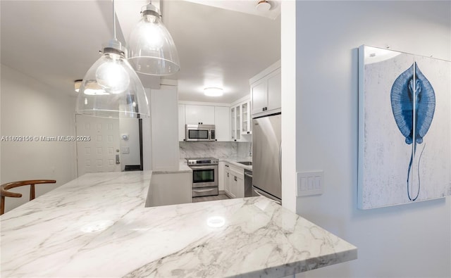 6061 Collins Ave Unit 7D, Miami Beach, FL 33140 - kitchen with stainless steel appliances, light stone counters, white cabinets, glass insert cabinets, and tasteful backsplash