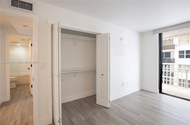 6061 Collins Ave Unit 7D, Miami Beach, FL 33140 - unfurnished bedroom with light wood-style flooring, a closet, and baseboards