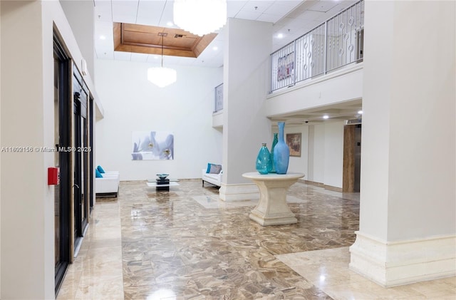 6061 Collins Ave Unit 7D, Miami Beach, FL 33140 - corridor featuring a high ceiling, marble tiled floors, and a raised ceiling
