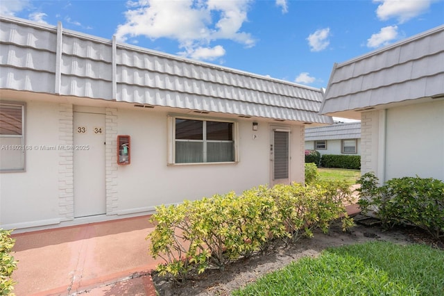 entrance to property with mansard roof and stucco siding