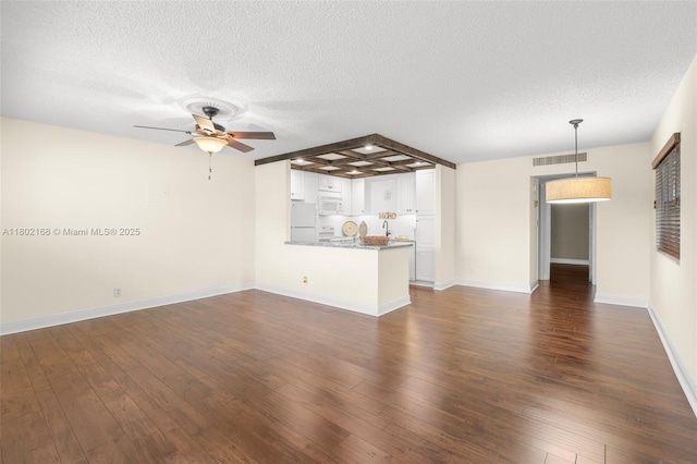 unfurnished living room featuring a ceiling fan, a textured ceiling, dark wood finished floors, and baseboards