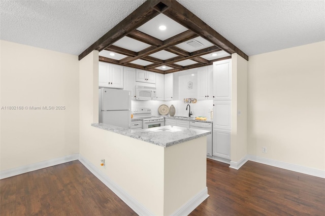 kitchen featuring white appliances, a sink, a peninsula, beam ceiling, and dark wood finished floors