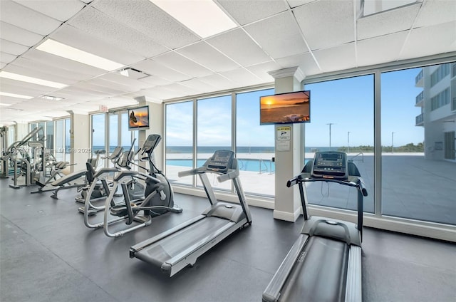 gym with a wall of windows, healthy amount of natural light, and a drop ceiling