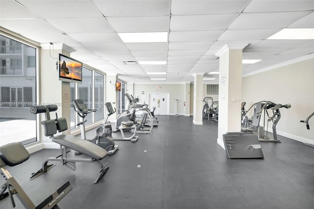 workout area with ornate columns, baseboards, a paneled ceiling, and ornamental molding