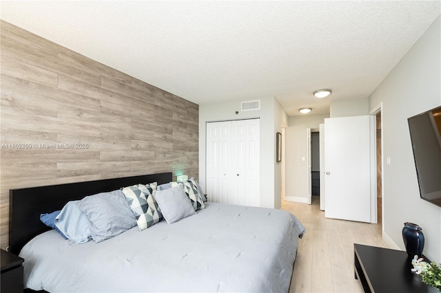 900 Saint Charles Pl Unit 621, Pembroke Pines, FL 33026 - bedroom with light wood-style floors, a closet, wood walls, an accent wall, and a textured ceiling
