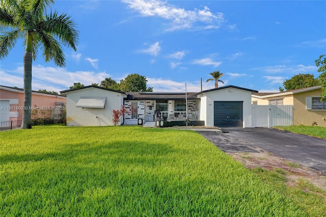 7908 Coral Blvd, Miramar, FL 33023 - ranch-style house with asphalt driveway, roof mounted solar panels, a garage, stucco siding, and a gate