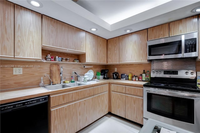 kitchen with appliances with stainless steel finishes, a sink, decorative backsplash, light brown cabinets, and recessed lighting