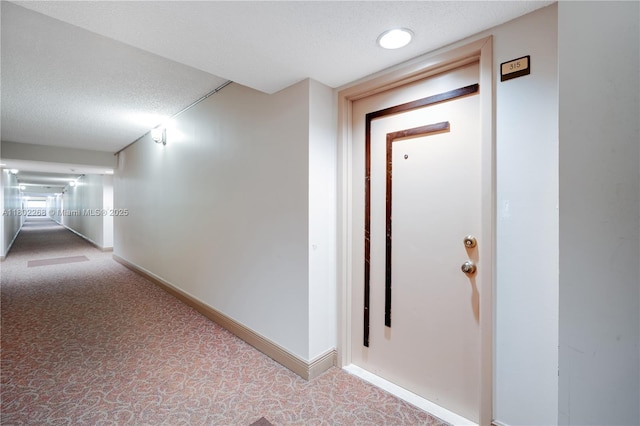 hall featuring carpet flooring, a textured ceiling, and baseboards