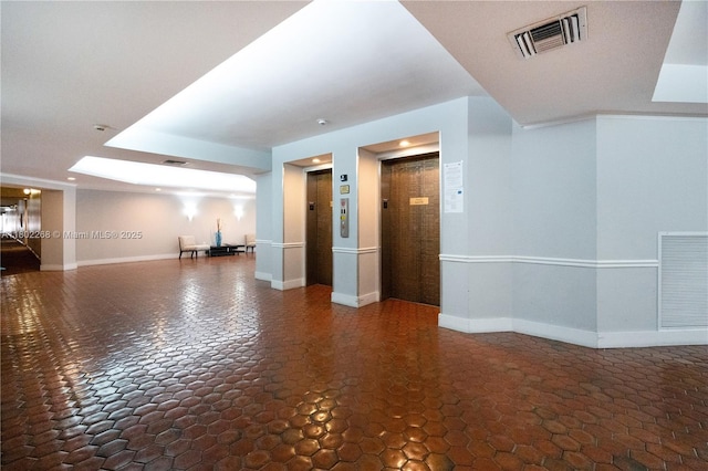unfurnished living room featuring elevator and baseboards