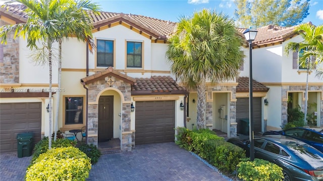 6973 Broadland Way, Coconut Creek, FL 33073 - view of front facade featuring a tiled roof, stone siding, stucco siding, decorative driveway, and a garage