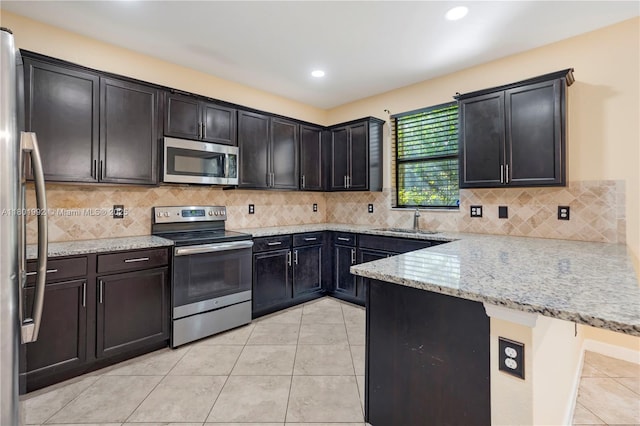6973 Broadland Way, Coconut Creek, FL 33073 - kitchen featuring stainless steel appliances, a sink, a peninsula, light tile patterned flooring, and light stone counters