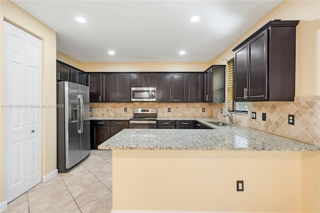 6973 Broadland Way, Coconut Creek, FL 33073 - kitchen with appliances with stainless steel finishes, a sink, a peninsula, dark brown cabinetry, and light tile patterned floors