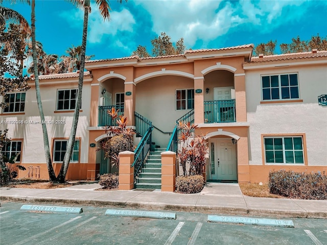 1241 SE 29th St Unit 203-27, Homestead, FL 33035 - view of front of house featuring stucco siding, stairs, uncovered parking, and a tile roof