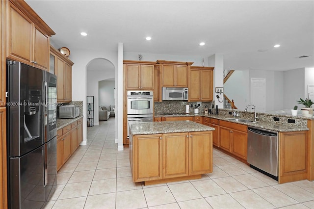 4968 SW 183rd Ave, Miramar, FL 33029 - kitchen with stainless steel appliances, a sink, a peninsula, arched walkways, and decorative backsplash