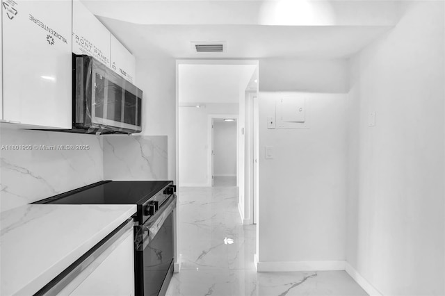 20335 W Country Club Dr Unit 1108, Aventura, FL 33180 - kitchen featuring black electric range oven, stainless steel microwave, white cabinetry, light marble finish floors, and baseboards