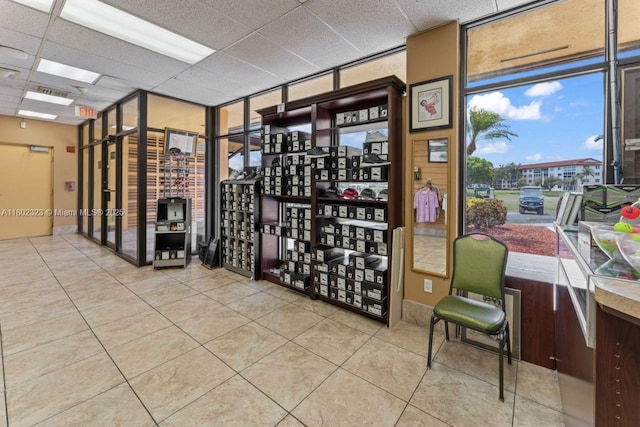wine cellar featuring tile patterned flooring, a drop ceiling, and a wall of windows
