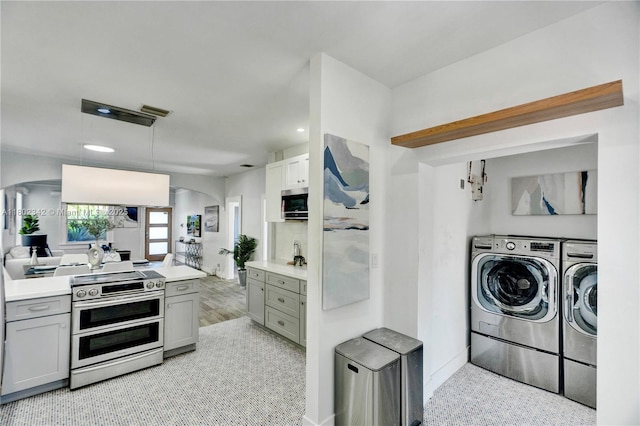 38 NW 47th Ter, Miami, FL 33127 - kitchen featuring washing machine and dryer, arched walkways, gray cabinetry, stainless steel appliances, and recessed lighting
