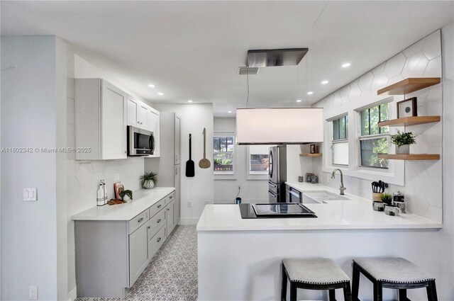 38 NW 47th Ter, Miami, FL 33127 - kitchen featuring stainless steel appliances, a sink, open shelves, a peninsula, and recessed lighting