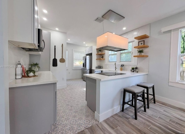 38 NW 47th Ter, Miami, FL 33127 - kitchen featuring open shelves, appliances with stainless steel finishes, a peninsula, a breakfast bar, and light countertops