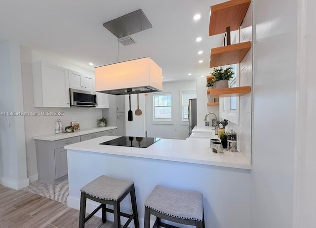 38 NW 47th Ter, Miami, FL 33127 - kitchen featuring open shelves, black electric cooktop, a peninsula, stainless steel microwave, and recessed lighting