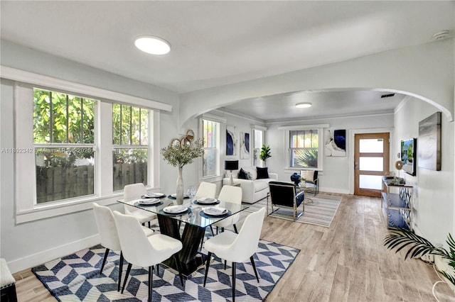 38 NW 47th Ter, Miami, FL 33127 - dining space with arched walkways, baseboards, and light wood-style floors