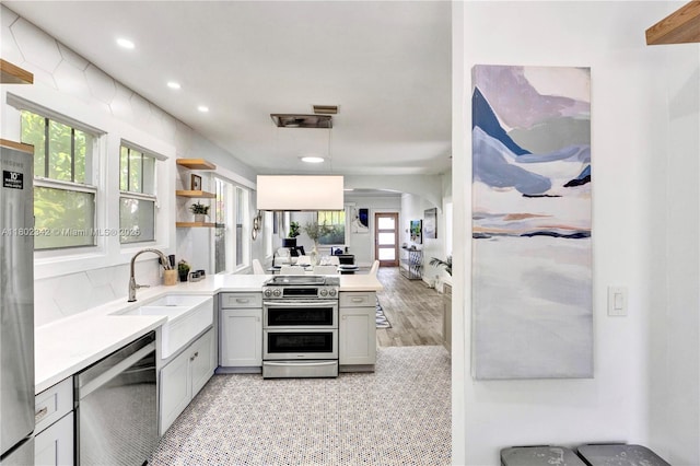 38 NW 47th Ter, Miami, FL 33127 - kitchen with appliances with stainless steel finishes, a sink, arched walkways, a peninsula, and plenty of natural light