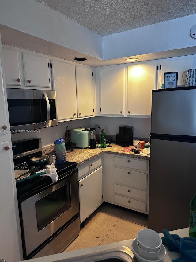 3310 N Pinewalk Dr N Unit 1814, Margate, FL 33063 - kitchen featuring stainless steel appliances, a textured ceiling, white cabinets, and light tile patterned flooring