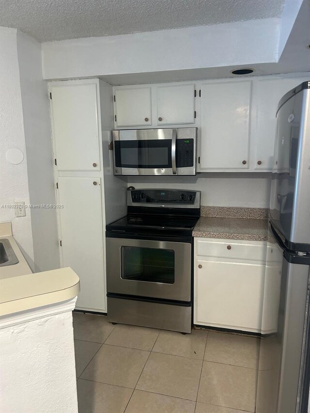 3310 N Pinewalk Dr N Unit 1814, Margate, FL 33063 - kitchen with appliances with stainless steel finishes, light tile patterned flooring, white cabinets, and a textured ceiling