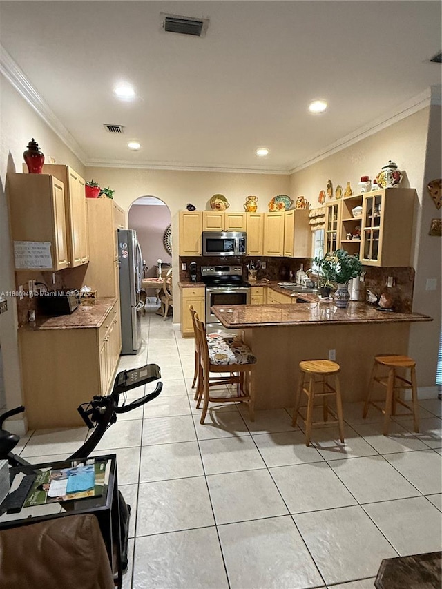 8943 NW 174th St, Hialeah, FL 33018 - kitchen with stainless steel appliances, arched walkways, a peninsula, light tile patterned flooring, and light brown cabinetry