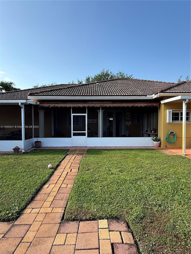 8943 NW 174th St, Hialeah, FL 33018 - rear view of property with a sunroom, a tiled roof, a lawn, and stucco siding