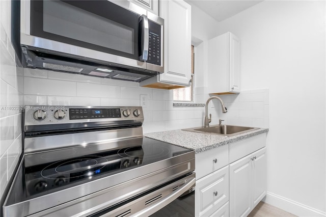 1661 SW 3rd St Unit 8, Miami, FL 33135 - kitchen with stainless steel appliances, a sink, white cabinetry, decorative backsplash, and baseboards